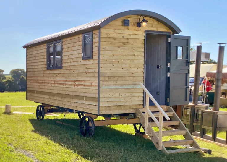 The Hideaway exterior with end door and steps in a natural wood finish by Belringham Shepherd Huts