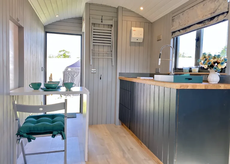 The Hideaway hut with Folding Table and clever wall hanging of chairs by Belringham Shepherd Huts