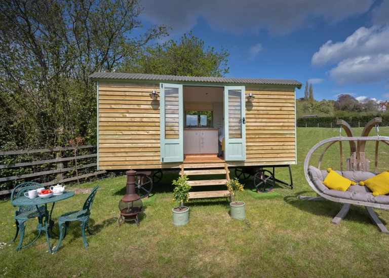 The Lookout 2 exterior has natural wood shiplap boards and a centred double door entrance with steps by Belringham Shepherd Huts Cover