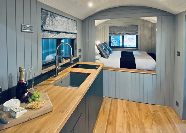 The Lookout bed area and Kitchenette with wood work surface and laminate floor by Belringham Shepherd Huts
